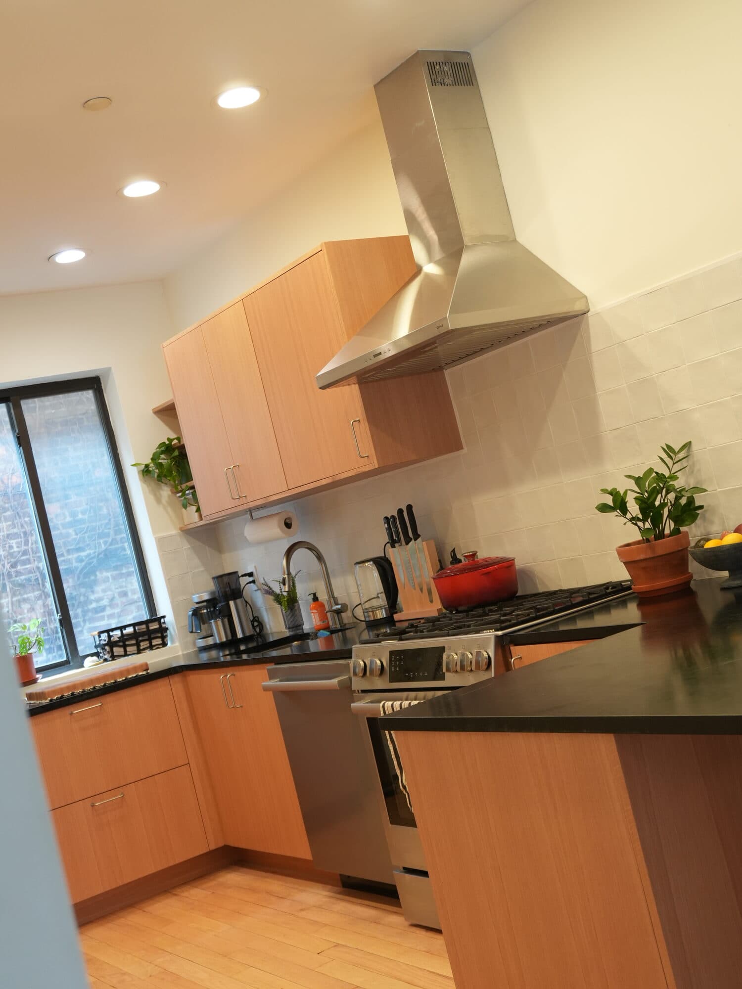 Renovated Greenpoint kitchen with light oak cabinetry, stainless hood, and peninsula