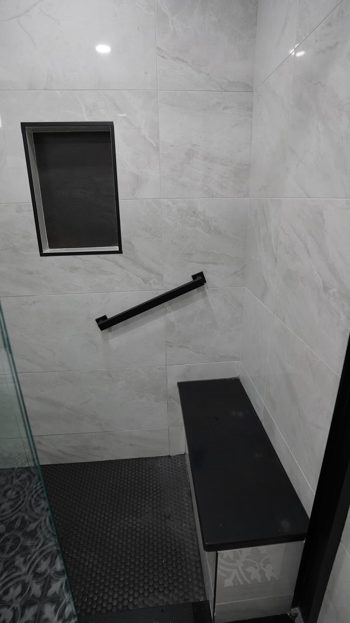 Tiled shower niche and corner shelving with black accent tile