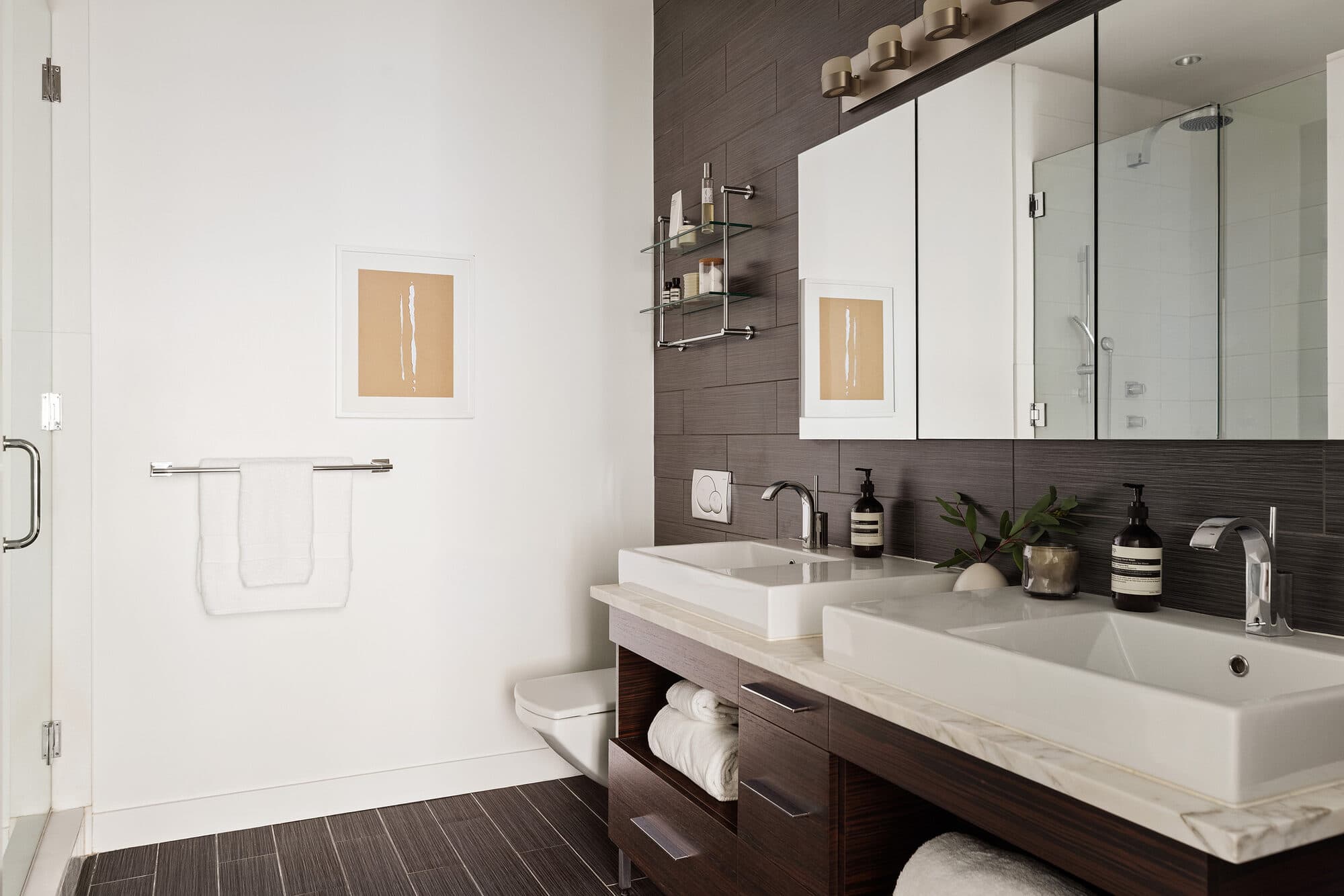 Renovated bathroom with double vessel sinks and dark tile accent wall