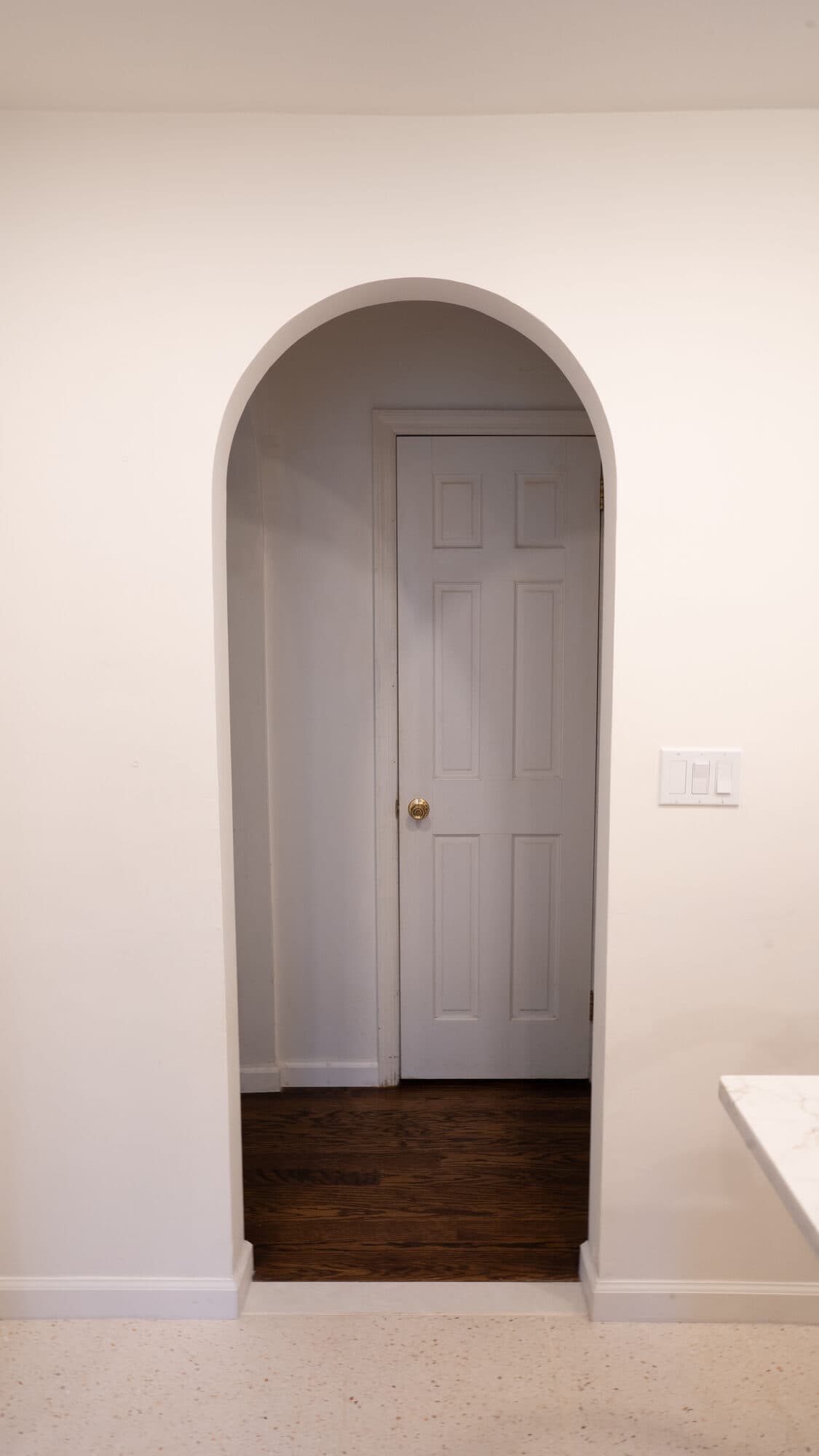 Arched doorway connecting the renovated kitchen to the hallway